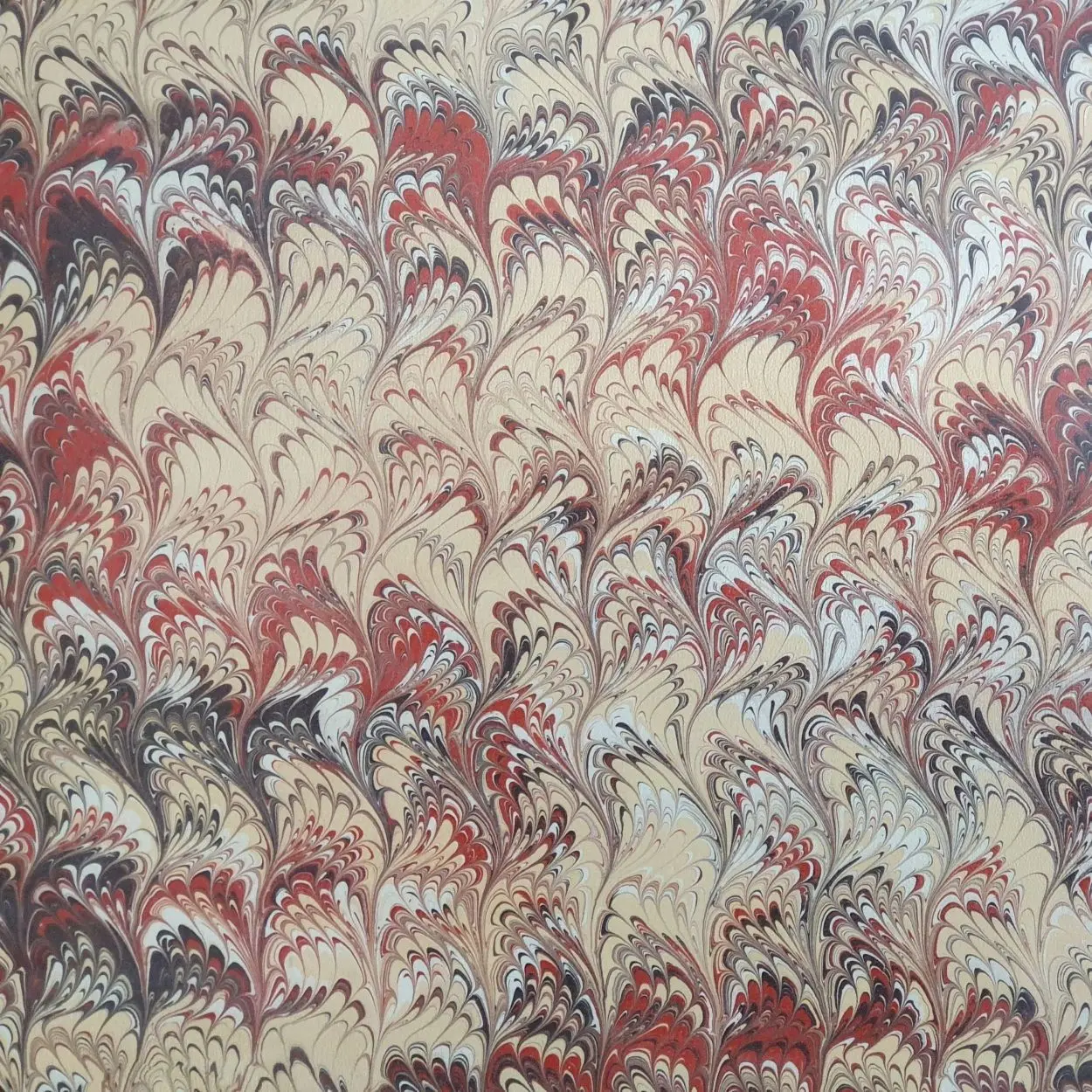 Traditionell marmoriertes Papier mit dichter Kammstruktur in Rot- und Grautönen, handbemalt